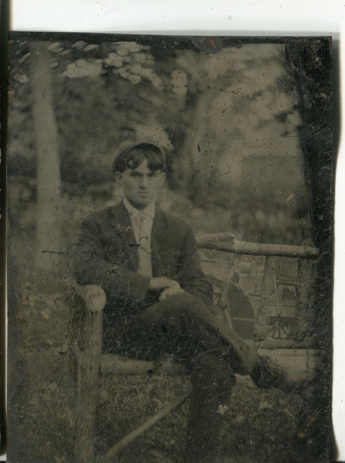 Tintype photo, man on rough wood bench, outside backdrop, antique vintage photo