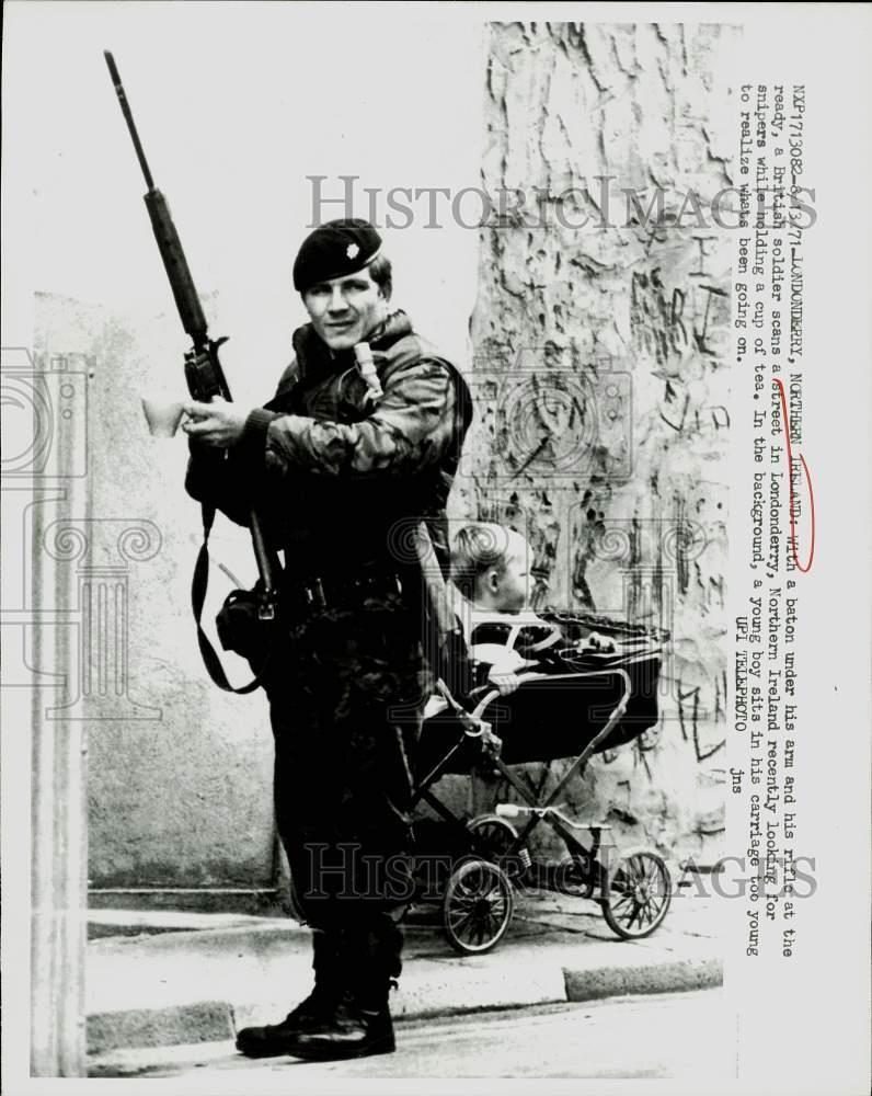 1971 Press Photo Armed British soldier and youngster in carriage in Londonderry. 1971 Press Photo Armed British soldier and youngster in carriage in Londonderry.